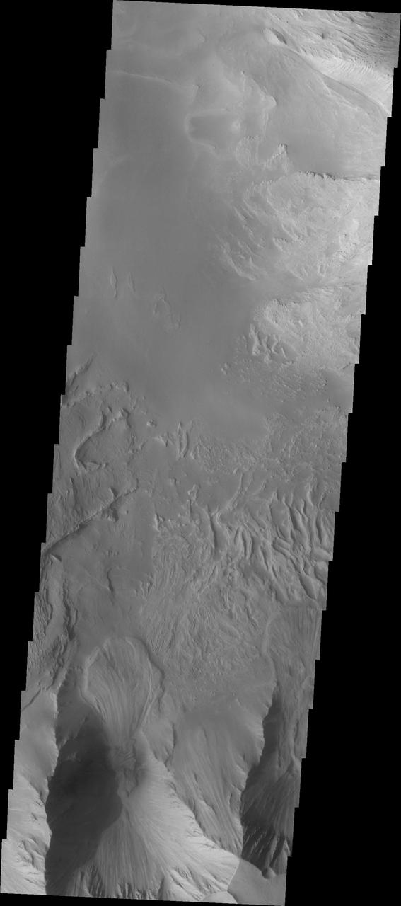 This image shows part of eastern Candor Chasma. At the bottom of the image is the steep cliff between the upper surface elevation and the depths of Candor Chasma. The small lobate feature at the base of the cliff in the bottom of the image is a landslide deposit formed by failure of the cliff face and gravitational downslope movement of the material.  Candor Chasma is one of the largest canyons that make up Valles Marineris. It is approximately 810 km long (503 miles) and has is divided into two regions - eastern and western Candor. Candor is located south of Ophir Chasma and north of Melas Chasma. The border with Melas Chasma contains many large landslide deposits. The floor of Candor Chasma includes a variety of landforms, including layered deposits, dunes, landslide deposits and steep sided cliffs and mesas. Many forms of erosion have shaped Chandor Chasma. There is evidence of wind and water erosion, as well as significant gravity driven mass wasting (landslides).  The Odyssey spacecraft has spent over 15 years in orbit around Mars, circling the planet more than 69000 times. It holds the record for longest working spacecraft at Mars. THEMIS, the IR/VIS camera system, has collected data for the entire mission and provides images covering all seasons and lighting conditions. Over the years many features of interest have received repeated imaging, building up a suite of images covering the entire feature. From the deepest chasma to the tallest volcano, individual dunes inside craters and dune fields that encircle the north pole, channels carved by water and lava, and a variety of other feature, THEMIS has imaged them all. For the next several months the image of the day will focus on the Tharsis volcanoes, the various chasmata of Valles Marineris, and the major dunes fields. We hope you enjoy these images!  Orbit Number: 8916 Latitude: -7.95016 Longitude: 293.509 Instrument: VIS Captured: 2003-12-18 11:38  https://photojournal.jpl.nasa.gov/catalog/PIA22162