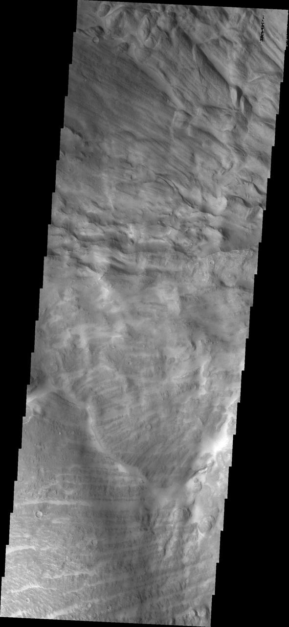 This VIS image shows part of the border between Chandor and Melas Chasmata. The entire image is landslide deposits. It is very common for landslides to develop linear surface grooves that parallel the direction of flow.  Candor Chasma is one of the largest canyons that make up Valles Marineris. It is approximately 810 km long (503 miles) and has is divided into two regions - eastern and western Candor. Candor is located south of Ophir Chasma and north of Melas Chasma. The border with Melas Chasma contains many large landslide deposits. The floor of Candor Chasma includes a variety of landforms, including layered deposits, dunes, landslide deposits and steep sided cliffs and mesas. Many forms of erosion have shaped Chandor Chasma. There is evidence of wind and water erosion, as well as significant gravity driven mass wasting (landslides).  The Odyssey spacecraft has spent over 15 years in orbit around Mars, circling the planet more than 69000 times. It holds the record for longest working spacecraft at Mars. THEMIS, the IR/VIS camera system, has collected data for the entire mission and provides images covering all seasons and lighting conditions. Over the years many features of interest have received repeated imaging, building up a suite of images covering the entire feature. From the deepest chasma to the tallest volcano, individual dunes inside craters and dune fields that encircle the north pole, channels carved by water and lava, and a variety of other feature, THEMIS has imaged them all. For the next several months the image of the day will focus on the Tharsis volcanoes, the various chasmata of Valles Marineris, and the major dunes fields. We hope you enjoy these images!  Orbit Number: 17003 Latitude: -8.20616 Longitude: 288.108 Instrument: VIS Captured: 2005-10-14 07:36  https://photojournal.jpl.nasa.gov/catalog/PIA22167