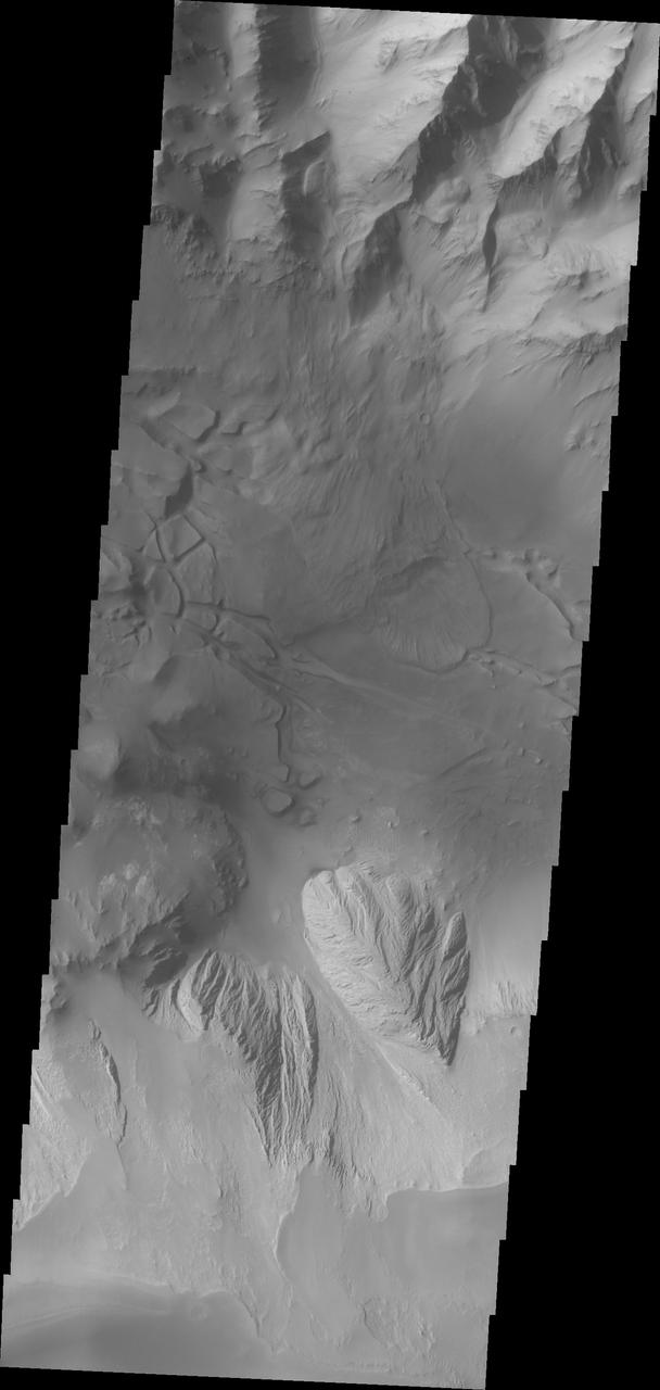 This image shows part of eastern Candor Chasma. At the top of the image is the steep cliff between the upper surface elevation and the depths of Candor Chasma. The bottom of the image is the cliff side of a large mesa. The two cliff faces have very different appearances. The cliff face between the top of the canyon and the bottom is likely layers of volcanic flows from the nearby Tharsis volcanoes. The mesa, however, is probably layers of sediments deposited in the canyon from wind, water and gravity driven erosion and deposition. These layered materials are much more easily eroded than the solid rock of the canyon sides. There is a landslide that originate from the northern cliff face and ran out into the canyon floor, visible as the lobate "tongue" at the right near the center of the image. Candor Chasma is one of the largest canyons that make up Valles Marineris. It is approximately 810 km long (503 miles) and has is divided into two regions - eastern and western Candor. Candor is located south of Ophir Chasma and north of Melas Chasma. The border with Melas Chasma contains many large landslide deposits. The floor of Candor Chasma includes a variety of landforms, including layered deposits, dunes, landslide deposits and steep sided cliffs and mesas. Many forms of erosion have shaped Chandor Chasma. There is evidence of wind and water erosion, as well as significant gravity driven mass wasting (landslides). The Odyssey spacecraft has spent over 15 years in orbit around Mars, circling the planet more than 69000 times. It holds the record for longest working spacecraft at Mars. THEMIS, the IR/VIS camera system, has collected data for the entire mission and provides images covering all seasons and lighting conditions. Over the years many features of interest have received repeated imaging, building up a suite of images covering the entire feature. From the deepest chasma to the tallest volcano, individual dunes inside craters and dune fields that encircle the north pole, channels carved by water and lava, and a variety of other feature, THEMIS has imaged them all. For the next several months the image of the day will focus on the Tharsis volcanoes, the various chasmata of Valles Marineris, and the major dunes fields. We hope you enjoy these images! Orbit Number: 36232 Latitude: -6.78692 Longitude: 292.732 Instrument: VIS Captured: 2010-02-13 14:46 https://photojournal.jpl.nasa.gov/catalog/PIA22170