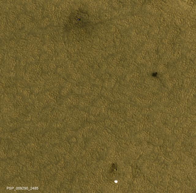 This is one of two images taken nearly a decade apart of NASA's Mars Phoenix Lander and related hardware around the mission's May 25, 2008, landing site on far-northern Mars. By late 2017, dust had obscured much of what was visible two months after the landing.  Both images were taken by the High Resolution Imaging Science Experiment (HiRISE) camera on NASA's Mars Reconnaissance Orbiter. The one with three patches of darker ground -- where landing events removed dust -- was taken on July 20, 2008. It is Fig. 1, an excerpt of HiRISE observation PSP_009290_2485. The one with a more even coating of pale dust throughout the area was taken on Dec. 21, 2017. It is Fig. 2, an excerpt of HiRISE observation ESP_053451_2485. Both cover an area roughly 300 meters wide at 68 degrees north latitude, 234 degrees east longitude, and the two are closely matched in viewing and illumination geometry, from about five Martian years apart in northern hemisphere summers.  An animation comparing the two images shows a number of changes between mid-2008 and late 2017. The lander (top) appears darker, and is now covered by dust. The dark spot created by the heat shield impact (right) is brighter, again due to dust deposition. The back shell and parachute (bottom) shows a darker parachute and brighter area of impact disturbance, thanks again to deposits of dust. We also see that the parachute has shifted in the wind, moving to the east.  In August 2008, Phoenix completed its three-month mission studying Martian ice, soil and atmosphere. The lander worked for two additional months before reduced sunlight caused energy to become insufficient to keep the lander functioning. The solar-powered robot was not designed to survive through the dark and cold conditions of a Martian arctic winter.  An animation and both images are available at https://photojournal.jpl.nasa.gov/catalog/PIA22223