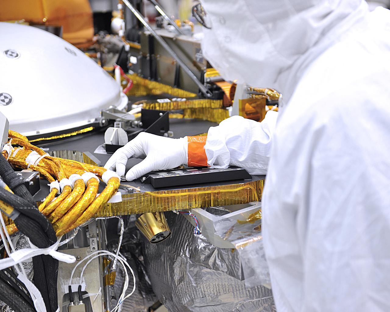 An engineer in the clean room at Lockheed Martin Space in Littleton, Colorado, affixes a dime-size chip onto the lander deck of NASA's InSight spacecraft. This second microchip, contains 1.6 million names submitted by the public to ride along with InSight to Mars. The chip was installed on Jan. 23, 2018. This joins another microchip that was previously installed that included 800,000 names for a grand total of 2.4 million names going to Mars as early as May 5, 2018. Engineers at NASA's Jet Propulsion Laboratory, Pasadena, California, put the names onto this tiny 0.3 square inches (8 millimeter-square) silicon wafer microchip using an electron beam to write extremely tiny letters with lines smaller than one one-thousandth the width of a human hair. The dime-size chip is affixed to the InSight lander deck and will remain on Mars forever. Normally used to make high-precision nanometer-scale devices, this technique was also used to write millions of names that were transported on NASA Mars rovers and Orion's first test flight. InSight is the first Mars mission dedicated to study the deep interior of Mars. Its findings will advance understanding of the early history of all rocky planets, including Earth. https://photojournal.jpl.nasa.gov/catalog/PIA22236