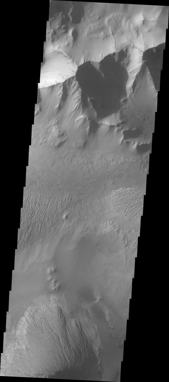 This VIS image shows part of Tithonium Chasma. The ridge visible at the top of the image is not the top of the canyon. The top of the canyon is off the image to the north. A lobate "tongue" visible between the ridge and the top of the canyon is the deposit left by a landslide event. This material is more resistant and forms the ridges extending down the canyon walls. Eroded materials cover much of the canyon floor. The initial formation of layered floor desposits was possibly created of air fall of dust, sand, and volcanic materials and water lain materials. The weathering of these deposits is probably by the wind. Loose sand and dust can be seen in other portions of this image.  Tithonium Chasma is at the western end of Valles Marineris. Valles Marineris is over 4000 kilometers long, wider than the United States. Tithonium Chasma is almost 810 kilometers long (499 miles), 50 kilometers wide and over 6 kilometers deep. In comparison, the Grand Canyon in Arizona is about 175 kilometers long, 30 kilometers wide, and only 2 kilometers deep. The canyons of Valles Marineris were formed by extensive fracturing and pulling apart of the crust during the uplift of the vast Tharsis plateau. Landslides have enlarged the canyon walls and created deposits on the canyon floor. Weathering of the surface and influx of dust and sand have modified the canyon floor, both creating and modifying layered materials.  The Odyssey spacecraft has spent over 15 years in orbit around Mars, circling the planet more than 71,000 times. It holds the record for longest working spacecraft at Mars. THEMIS, the IR/VIS camera system, has collected data for the entire mission and provides images covering all seasons and lighting conditions. Over the years many features of interest have received repeated imaging, building up a suite of images covering the entire feature. From the deepest chasma to the tallest volcano, individual dunes inside craters and dune fields that encircle the north pole, channels carved by water and lava, and a variety of other feature, THEMIS has imaged them all. For the next several months the image of the day will focus on the Tharsis volcanoes, the various chasmata of Valles Marineris, and the major dunes fields. We hope you enjoy these images!  Orbit Number: 3212 Latitude: -4.46108 Longitude: 271.004 Instrument: VIS Captured: 2002-09-04 22:56  https://photojournal.jpl.nasa.gov/catalog/PIA22268