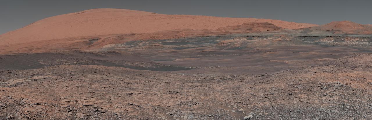 This mosaic taken by NASA's Mars Curiosity rover looks uphill at Mount Sharp, which Curiosity has been climbing. Spanning the center of the image is an area with clay-bearing rocks that scientists are eager to explore; it could shed additional light on the role of water in creating Mount Sharp. The mosaic was assembled from dozens of images taken by Curiosity's Mast Camera (Mastcam). It was taken on Sol 1931 back in January.  Mount Sharp stands in the middle of Gale Crater, which is 96 miles (154 kilometers) in diameter. This mound, which Curiosity has been climbing since 2014, likely formed in the presence of water at various points of time in Mars ancient history. That makes it an ideal place to study how water influenced the habitability of Mars billions of years ago.  The scene has been white-balanced so the colors of the rock materials resemble how they would appear under daytime lighting conditions on Earth.  https://photojournal.jpl.nasa.gov/catalog/PIA22313