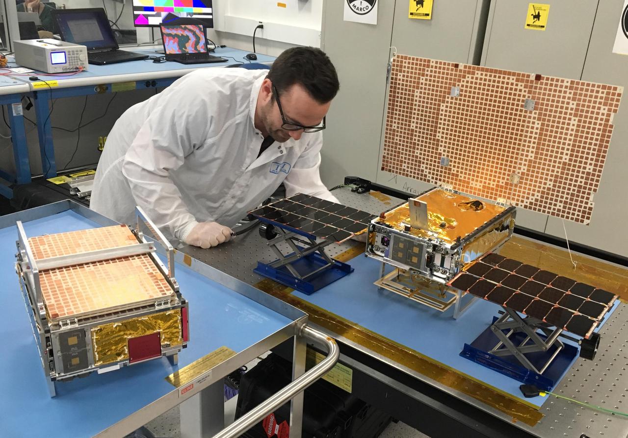 Engineer Joel Steinkraus stands with both of the Mars Cube One (MarCO) spacecraft at NASA's Jet Propulsion Laboratory. The one on the left is folded up the way it will be stowed on its rocket; the one on the right has its solar panels fully deployed, along with its high-gain antenna on top. The MarCOs will be the first CubeSats -- a kind of modular, mini-satellite -- flown in deep space. They're designed to fly along behind NASA's InSight lander on its cruise to Mars. If they make the journey, they will test a relay of data about InSight's entry, descent and landing back to Earth. Though InSight's mission will not depend on the success of the MarCOs, they will be a test of how CubeSats can be used in deep space.  https://photojournal.jpl.nasa.gov/catalog/PIA22319