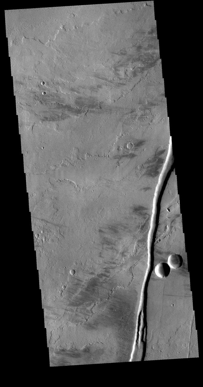 The linear channel in the bottom half of this VIS image is part of Olympica Fossae. Olympica Fossae is a complex channel form located on the Tharsis plains between Alba Mons and Olympus Mons. It was most likely created by volcanic flows, but was probably also affected by the formation of graben in the region. Graben are formed by the down-drop of material between paired faults. The collapse of the Alba Mons volcano resulted in a huge region of graben. Orbit Number: 71495 Latitude: 22.7947 Longitude: 242.683 Instrument: VIS Captured: 2018-01-26 01:24 https://photojournal.jpl.nasa.gov/catalog/PIA22396