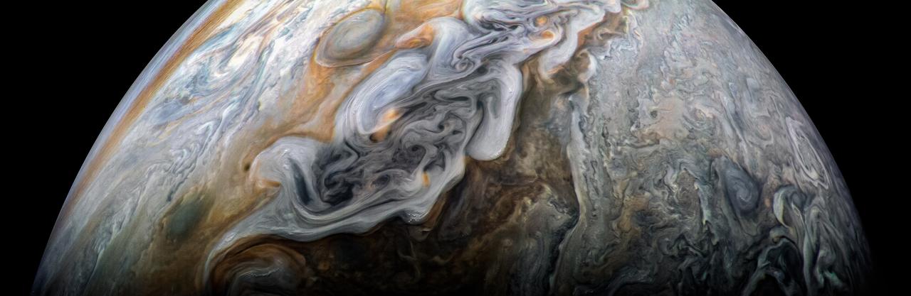 This image captures the intensity of the jets and vortices in Jupiter's North North Temperate Belt. NASA's Juno spacecraft took this color-enhanced image at 10:31 p.m. PDT on May 23, 2018 (1:31 a.m. EDT on May 24), as Juno performed its 13th close flyby of Jupiter. At the time, the spacecraft was about 4,900 miles (7,900 kilometers) from the tops of the clouds of the gas giant planet at a northern latitude of about 41 degrees. The view is oriented with south on Jupiter toward upper left and north toward lower right. The North North Temperate Belt is the prominent reddish-orange band left of center. It rotates in the same direction as the planet and is predominantly cyclonic, which in the northern hemisphere means its features spin in a counter-clockwise direction. Within the belt are two gray-colored anticyclones. To the left of the belt is a brighter band (the North North Temperate Zone) with high clouds whose vertical relief is accentuated by the low angle of sunlight near the terminator. These clouds are likely made of ammonia-ice crystals, or possibly a combination of ammonia ice and water. Although the region as a whole appears chaotic, there is an alternating pattern of rotating, lighter-colored features on the zone's north and south sides. Scientists think the large-scale dark regions are places where the clouds are deeper, based on infrared observations made at the same time by Juno's JIRAM experiment and Earth-based supporting observations. Those observations show warmer, and thus deeper, thermal emission from these regions. To the right of the bright zone, and farther north on the planet, Jupiter's striking banded structure becomes less evident and a region of individual cyclones can be seen, interspersed with smaller, darker anticyclones. https://photojournal.jpl.nasa.gov/catalog/PIA22423 . - Enhanced image by Kevin M. Gill (CC-BY) based on images provided courtesy of NASA/JPL-Caltech/SwRI/MSSS