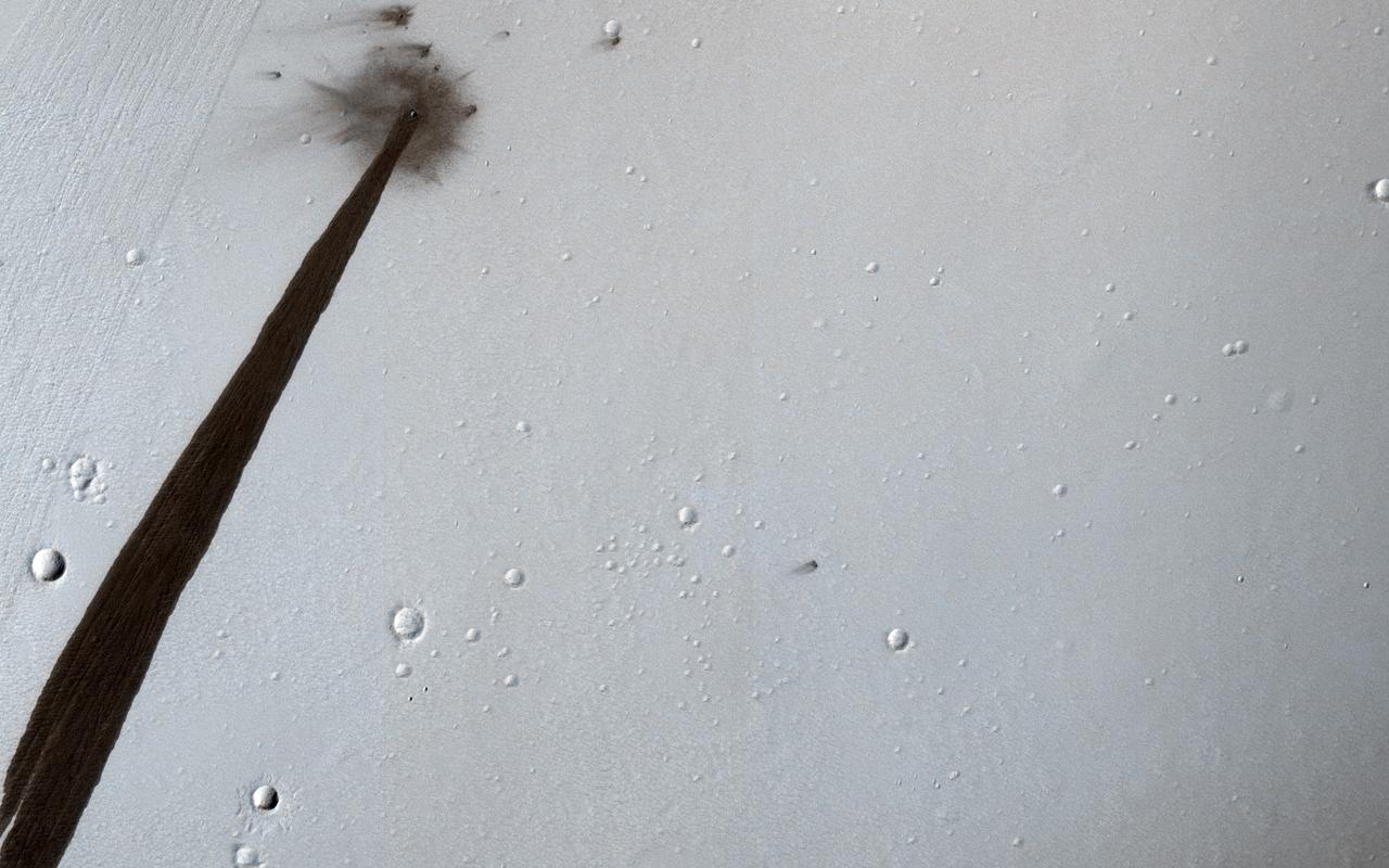 This HiRISE image from NASA's Mars Reconnaissance Orbiter (MRO) captures a new, dated (within about a decade) impact crater that triggered a slope streak. When the meteoroid hit the surface and exploded to make the crater, it also destabilized the slope and initiated this avalanche. The crater itself is only 5 meters across, but the streak it started is 1 kilometer long! Slope streaks are created when dry dust avalanches leave behind dark swaths on dusty Martian hills. The faded scar of an old avalanche is also visible to the side of the new dark streak. https://photojournal.jpl.nasa.gov/catalog/PIA22513