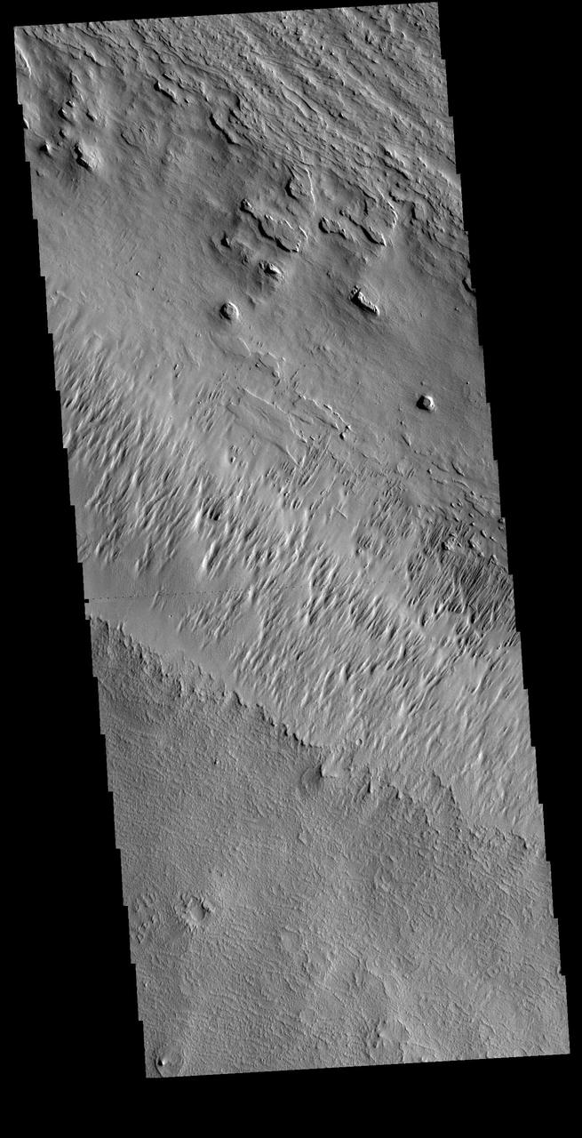 In regions of poorly cemented surface materials it is possible to create large features due to just the action of the wind. The equatorial region between Olympus Mons and Apollinaris Mons is dominated by wind etched regions. This region east of Apollinaris Mons contains just such a terrain. The direction of the wind aligns with the ridges and valleys. The dominant wind direction in this region is southeast to northwest; however, other wind directions can occur within a localized region.The top of this VIS image follows the regional trend, with a smaller central surface indicating winds perpendicular to the prevailing direction. Orbit Number: 72333 Latitude: -10.2083 Longitude: 179.736 Instrument: VIS Captured: 2018-04-05 02:02 https://photojournal.jpl.nasa.gov/catalog/PIA22577