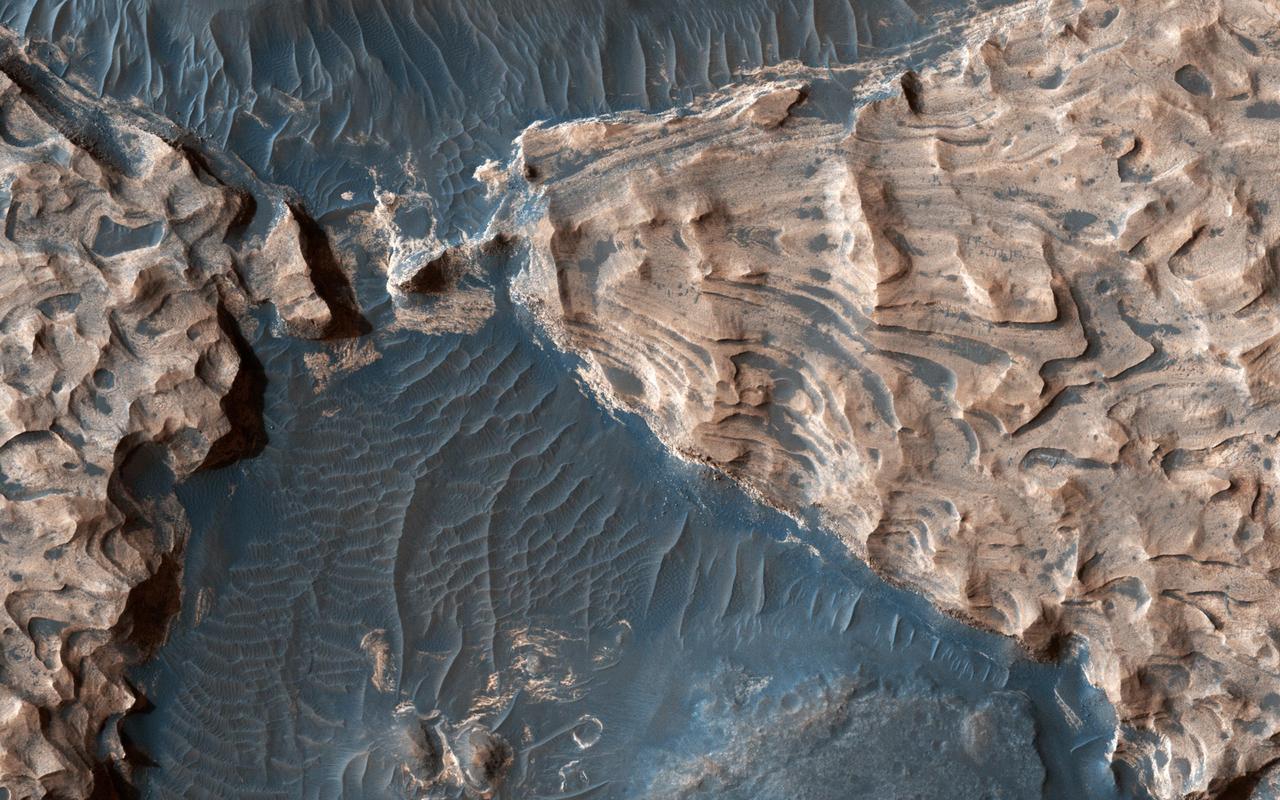 Acquired on April 1, 2018, this image from NASA's Mars Reconnaissance Orbiter shows Aram Chaos, a 280 kilometer-diameter ancient impact crater that lies within in the Southern Highlands of Mars. Uplifted blocks of light-toned layers, composed largely of the iron-oxide hematite and water-altered silicates, indicate that this crater once held a lake.  Scientists suggest that these enormous flood channels were carved quickly within just weeks or months by catastrophic outflows of groundwater over 2.5 billion years ago from beneath Aram Chaos and nearby regions. Today dark (basaltic) dunes fill most of the low regions and the etched areas of the uplifted blocks obscure much of the original crater floor.  Aram Chaos is located near the headwaters of Ares Vallis, a large outflow channel system that extends about 1700 kilometers towards the northwest across the ancient cratered highlands before emptying into the Northern Lowlands at Chryse Planitia near the Mars Pathfinder landing site.   More information is available at https://photojournal.jpl.nasa.gov/catalog/PIA22585