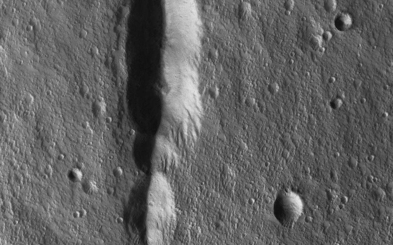 During the 2018 Mars dust storm, we obtained a clear view of the summit of the giant volcano Elysium Mons. We see the western rim and floor of the caldera, and a chain of pits (called a "catena") extending from the caldera towards the north. The chain of pits likely formed by volcanic processes, such as the collapse of a lava tube after it drained. Or by a tectonic process, such as a rift in the rocks below that drained loose material from the surface. An unexpected feature of this catena is the presence of avalanches in two of the pits (marked A and B in the cutout, with the uphill direction towards the top of the image.) The flows in both pits could be ancient, produced during the formation of the catena, but they are not found in the other pits in the chain. They might have formed more recently by the collapse of steep dust deposits like those in a degraded crater to the left of the catena. https://photojournal.jpl.nasa.gov/catalog/PIA22728