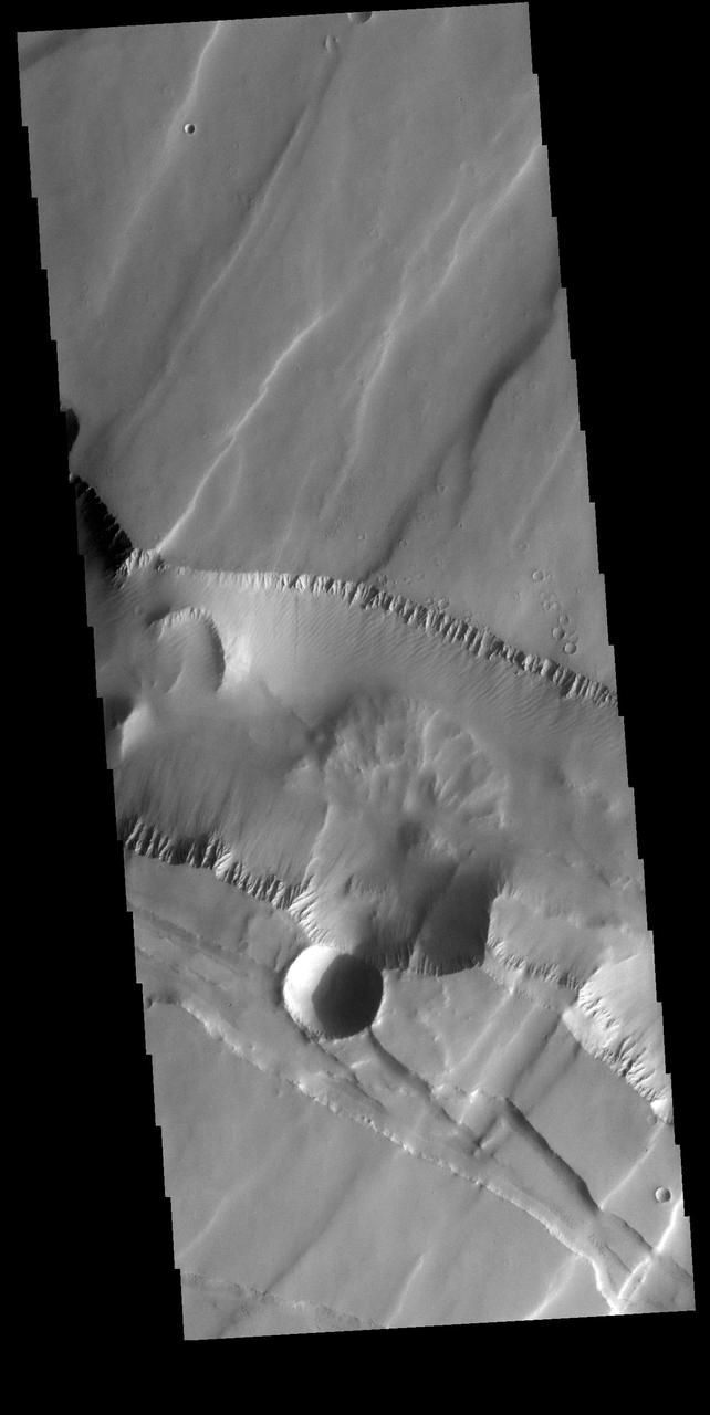 This VIS image is located in Noctis Labyrinthus. There are two directions of faults visible, which intersect at an approximately 90 degree angle. The faults running from bottom right to upper left are the younger set. The change in direction indicates a change in the tectonic stresses in the region. Orbit Number: 74276 Latitude: -6.04595 Longitude: 261.215 Instrument: VIS Captured: 2018-09-12 03:22 https://photojournal.jpl.nasa.gov/catalog/PIA22798