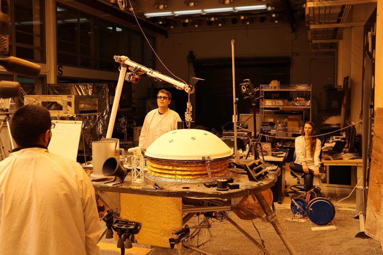 NASA's InSight mission tests an engineering version of the spacecraft's robotic arm in a Mars-like environment at NASA's Jet Propulsion Laboratory. The five-fingered grapple on the end of the robotic arm is lifting up the Wind and Thermal Shield, a protective covering for InSight's seismometer. The test is being conducted under reddish "Mars lighting" to simulate activities on the Red Planet. https://photojournal.jpl.nasa.gov/catalog/PIA22806