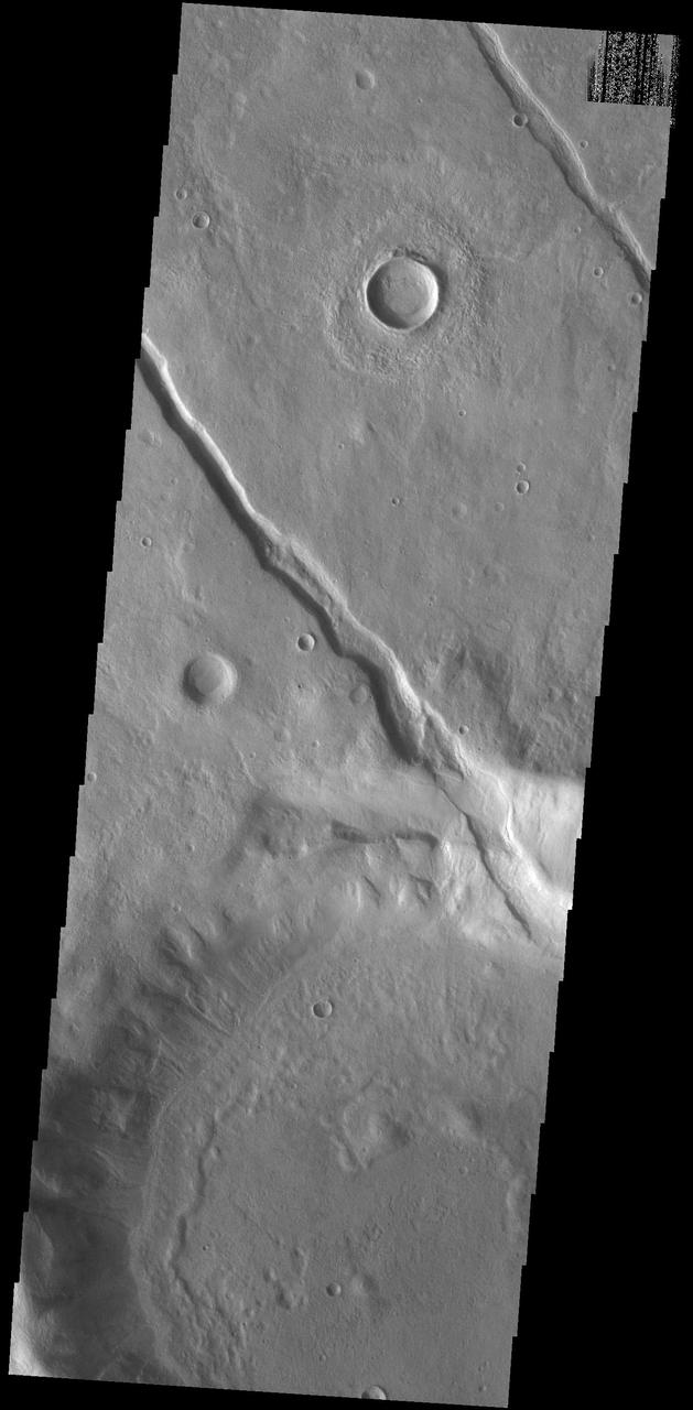 Located on the northern margin of Aonia Terra, this unnamed crater interacts with one of the fossa, also called a graben. In this image, it is apparent that the tectonic depression crosses the crater, which means the crater was created before the depression. The ability to relatively date the different features allows for interpretations of the series of events that created the features in this image. Orbit Number: 74806 Latitude: -42.6506 Longitude: 273.295 Instrument: VIS Captured: 2018-10-25 18:22 https://photojournal.jpl.nasa.gov/catalog/PIA22886