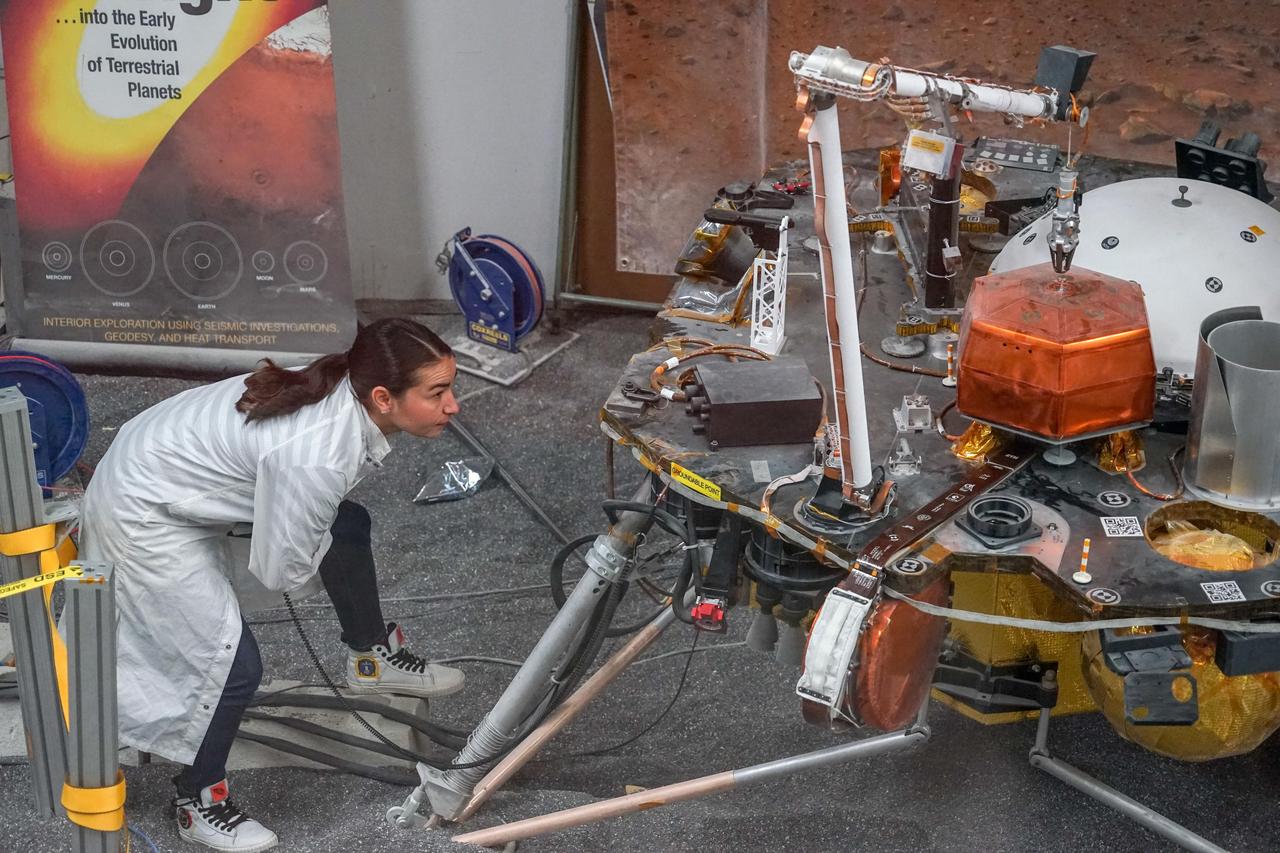 Engineer Marleen Sundgaard watches as a test version of NASA's Mars InSight lander grasps a model of the spacecraft's seismometer. This work was done at NASA's Jet Propulsion Laboratory in Pasadena, California.  https://photojournal.jpl.nasa.gov/catalog/PIA22952