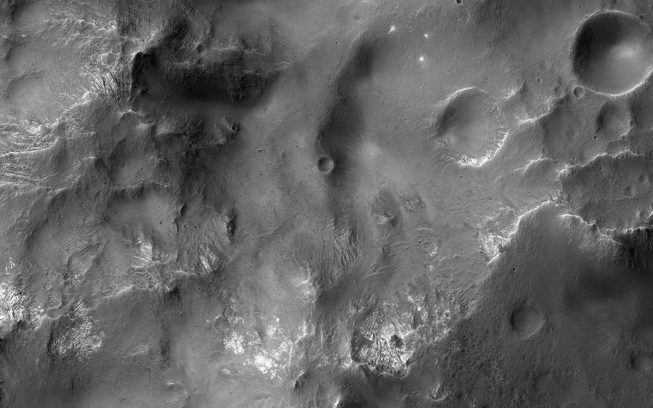 This image shows a cross-section of a complex crater in Terra Cimmeria. Starting in the center, we see a series of peaks with exposed bedrock. These peaks formed during the impact event when material that was originally several kilometers below the surface was uplifted and exposed. The impact also melted the rocks. This eventually cooled, forming the pitted materials that coat the crater floor around the uplift. The rim of the crater was unstable, and collapsed inwards to form terraces, and we see additional pitted materials between the terraces and the rim. Just outside the crater we can see dark-toned material that was excavated and thrown out after the impact. https://photojournal.jpl.nasa.gov/catalog/PIA23022