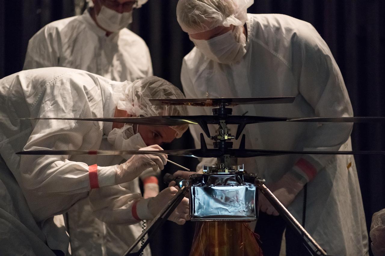 Members of NASA's Mars Helicopter team attach a thermal film enclosure to the fuselage of the flight model (the actual vehicle going to the Red Planet). The image was taken on Feb. 1, 2019, inside the Space Simulator, a 25-foot-wide (7.62-meter-wide) vacuum chamber at NASA's Jet Propulsion Laboratory in Pasadena, California.  https://photojournal.jpl.nasa.gov/catalog/PIA23157