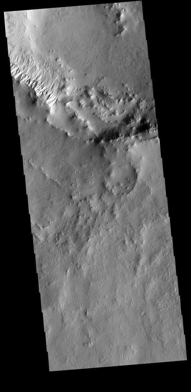 This VIS image shows part of the rim of an unnamed crater in Terra Cimmeria. A group of channels dissect the rim near to upper left of the image. These channels are called gullies due to being on a steep slope rather than a flat river plain. With careful examination, it is possible to see a boundary layer between the upper incised gully and a lower deposition region. The boundary marks a change in slope, the steep upper portion supports fast moving fluid that carves into the rim eroding materials. The change to a flatter slope causes the fluid to slow down and as it slows the materials carried by the fluid a deposited. Orbit Number: 75452 Latitude: -47.6995 Longitude: 170.871 Instrument: VIS Captured: 2018-12-17 23:46 https://photojournal.jpl.nasa.gov/catalog/PIA23185