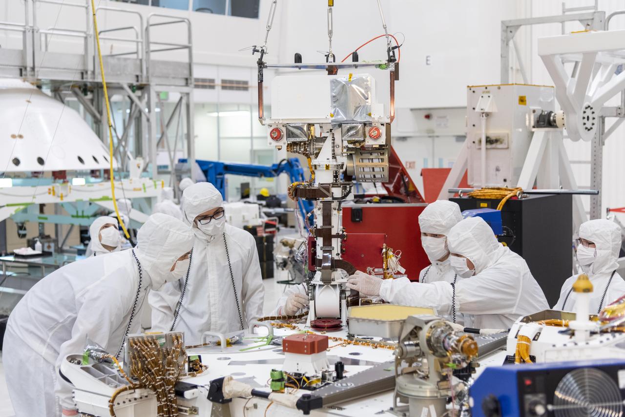 Engineers and technicians at NASA's Jet Propulsion Laboratory in Pasadena, California, install the remote sensing mast on the Mars 2020 rover.  The image was taken on June 5, 2019, in the Spacecraft Assembly Facility's High Bay 1 clean room at JPL.  https://photojournal.jpl.nasa.gov/catalog/PIA23268