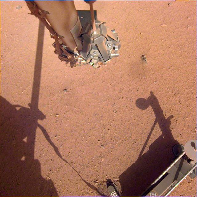 The robotic arm on NASA's Mars InSight lander moves in place over the Heat Flow and Physical Properties Package (HP3) and opens the fingers of its grapple in this series of images from June 1, 2019. Using the robotic arm, InSight engineers are preparing to lift the HP3 support structure -- the black device with four footpads pressed into the soil -- from where it was placed a few months ago on Mars. The instrument's self-hammering "mole" is partially buried beneath it. Engineers hope that by moving the support structure, they can use the robotic arm to help the mole dig deeper into the soil and take the temperature of Mars.  Movie available at https://photojournal.jpl.nasa.gov/catalog/PIA23277