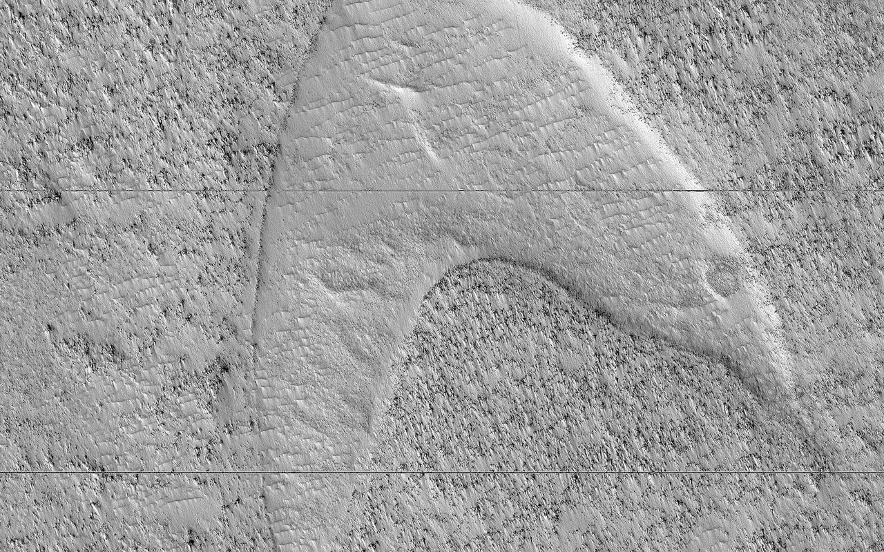 These curious chevron shapes in southeast Hellas Planitia are the result of a complex story of dunes, lava, and wind. Long ago, there were large crescent-shaped (barchan) dunes that moved across this area, and at some point, there was an eruption. The lava flowed out over the plain and around the dunes, but not over them. The lava solidified, but these dunes still stuck up like islands. However, they were still just dunes, and the wind continued to blow. Eventually, the sand piles that were the dunes migrated away, leaving these "footprints" in the lava plain. These are also called "dune casts" and record the presence of dunes that were surrounded by lava. Enterprising viewers will make the discovery that these features look conspicuously like a famous logo: and you'd be right, but it's only a coincidence. https://photojournal.jpl.nasa.gov/catalog/PIA23288