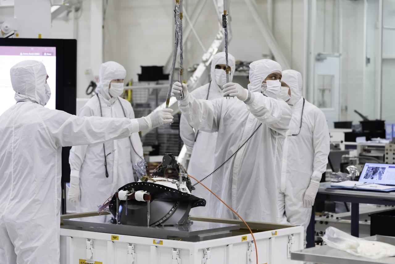 Engineers at NASA's Jet Propulsion Laboratory lift the Mars 2020 rover's bit carousel out of its storage container. The bit carousel is a mechanism that is at the heart of the rover's Sample Caching System. The image was taken on Aug. 5, 2019, in the Spacecraft Assembly Facility's High Bay 1 at JPL.  https://photojournal.jpl.nasa.gov/catalog/PIA23320