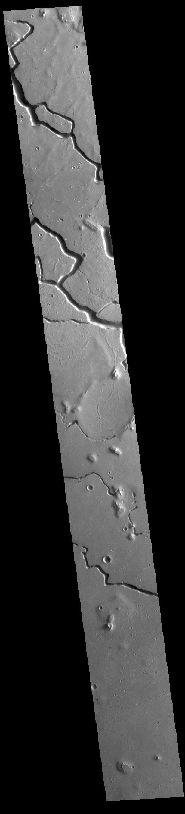 This VIS image is located in the central portion of Hephaestus Fossae. Hephaestus Fossae is a complex channel system in Utopia Planitia near Elysium Mons. It has been proposed that the channel formed by the release of melted subsurface ice during the impact event that created a large crater south of this image. Additionally, the nearby Elysium volcanic center created subsurface heating that may have played a part in creating both Hephaestus Fossae and Hebrus Valles to the north.  Orbit Number: 77487 Latitude: 18.8111 Longitude: 124.593 Instrument: VIS Captured: 2019-06-03 14:10  https://photojournal.jpl.nasa.gov/catalog/PIA23335