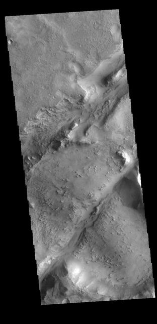 The two linear depressions in this VIS image are part of the Nili Fossae fracture system. Nili Fossae is the name of a collection of curved faults and down-dropped blocks of crust between the faults (called graben). The grabens lie northeast of the large volcano Syrtis Major and northwest of the ancient impact basin Isidis. The grabens make concentric curves that follow the outline of Isidis Planitia. The faults likely formed as the crust sagged under the weight of lava flows filling Isidis. Orbit Number: 77813 Latitude: 22.0638 Longitude: 78.198 Instrument: VIS Captured: 2019-06-30 10:29 https://photojournal.jpl.nasa.gov/catalog/PIA23390