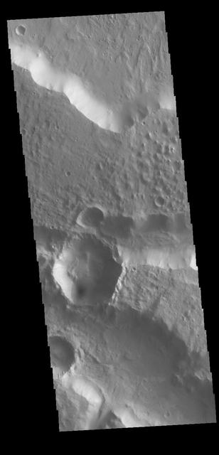 This image is located along the margin between Terra Cimmeria and Elysium Planitia. This boundary region is typified by tectonic fractures forming long, linear depressions. The crater in the lower half of the image has a hexagon shape rather than the normal circular outline. The regional surface/subsurface fracture system deflected the impact generated pressure waves along the tectonic network, causing the linear sides we see in the image. Meteor Crater in northern Arizona has a similar flat sided shape, in that case a square rather than a hexagon. The Arizona crater impacted into sandstone and limestone that had a right angle fracture system.  Orbit Number: 78210 Latitude: -7.13006 Longitude: 147.811 Instrument: VIS Captured: 2019-08-02 02:56  https://photojournal.jpl.nasa.gov/catalog/PIA23448