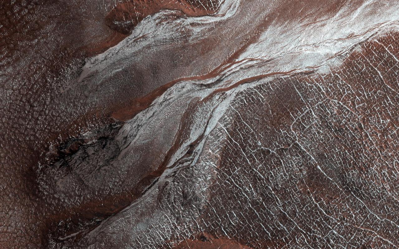 This image of a crater rim strikingly shows what appear to be bright white flows coming from gullies in the crater wall. However, HiRISE has been watching these gullies for some time (going all the way back to our first observation in 2012) and the flow features have been there for years. The new aspect is the bright white coloration, which is frost. This is the earliest in the springtime that this area has been observed, and just like some winter mornings here on Earth, the conditions on Mars can be just right for frost to form. The interesting thing is that the frost appears on the gully deposits and not as much on the surrounding rock, indicating the physical properties of the gully deposits are different. https://photojournal.jpl.nasa.gov/catalog/PIA23451