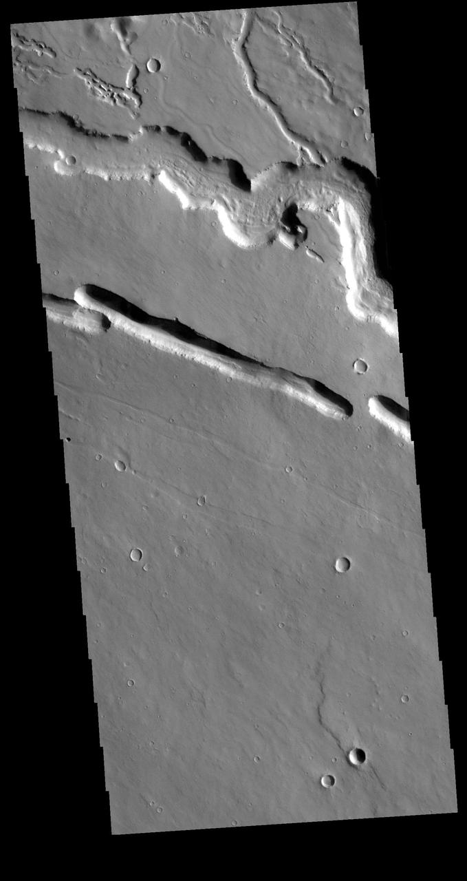 Today's VIS image shows part of Elysium Fossae, located on the western flank of the Elysium volcanic complex. The fossae have both a tectonic and a volcanic origin. The linear depressions, created by tectonic activity, are aligned southeast to northwest (the top of the image is north). The sinuous nature of the channel at the top of the image is due to the flow of a liquid, most likely lava in this case. Orbit Number: 78834 Latitude: 29.682 Longitude: 139.489 Instrument: VIS Captured: 2019-09-22 12:21 https://photojournal.jpl.nasa.gov/catalog/PIA23504