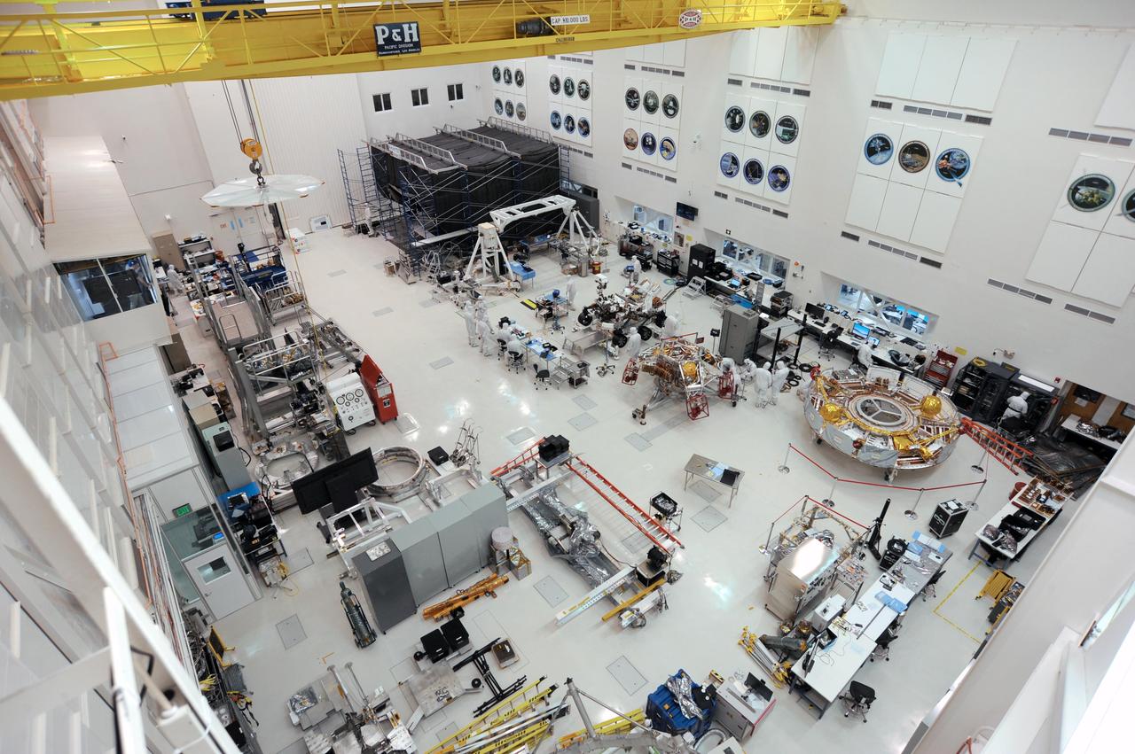The Mars 2020 rover is visible (just above center) in this image — taken on Nov. 12, 2019 — of the High Bay 1 clean room floor in JPL's Spacecraft Assembly Facility.  Many of NASA's most famous robotic spacecraft were assembled and tested in High Bay 1, including most of the Ranger and Mariner spacecraft; Voyager 1; the Galileo and Cassini orbiters; and all of NASA's Mars rovers. An annotated version of the image points to the facility's Wall of Fame, featuring emblems of those and other spacecraft that successfully launched after being built in the room. It also points to other features of the room, including the facility's gallery, which hosts about 30,000 members of the public each year.  https://photojournal.jpl.nasa.gov/catalog/PIA23519