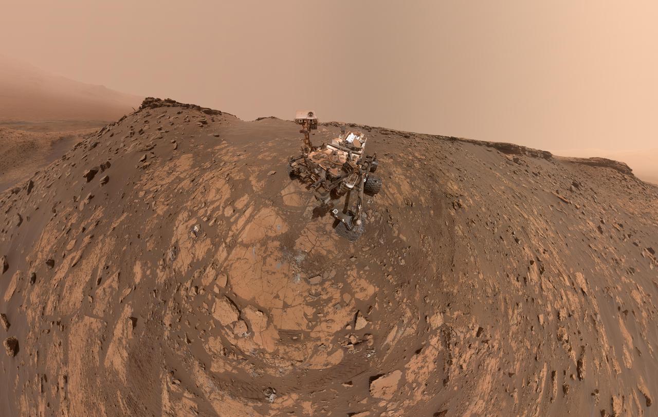 This selfie was taken by NASA's Curiosity Mars rover on Feb. 26, 2020 (the 2,687th Martian day, or sol, of the mission). The crumbling rock layer at the top of the image is the Greenheugh Pediment, which Curiosity climbed soon after taking the image.  Directly to the left of Curiosity's foremost wheel is a hole the rover drilled at a rock feature called "Hutton." The selfie includes 86 individual images taken by the Mars Hand Lens Imager (MAHLI) camera on the end of Curiosity's robotic arm. The images were then stitched into a panorama.  https://photojournal.jpl.nasa.gov/catalog/PIA23624