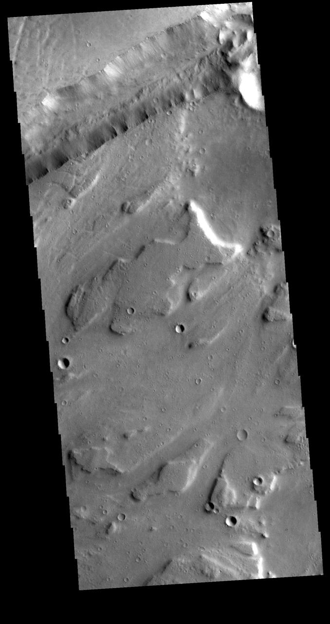 This VIS image shows part of Sacra Mensa, a large mesa located between the north and south channels of Kasei Valles. The linear feature at the top of the image is one of the many graben found in the mesa and surrounding highlands. Graben are formed by the downward motion of a block of material between paired tectonic faults. Sacra Mensa rises 3 km (almost 2 miles) above Kasei Valles. Orbit Number: 79203 Latitude: 26.0793 Longitude: 294.1 Instrument: VIS Captured: 2019-10-22 21:34 https://photojournal.jpl.nasa.gov/catalog/PIA23634