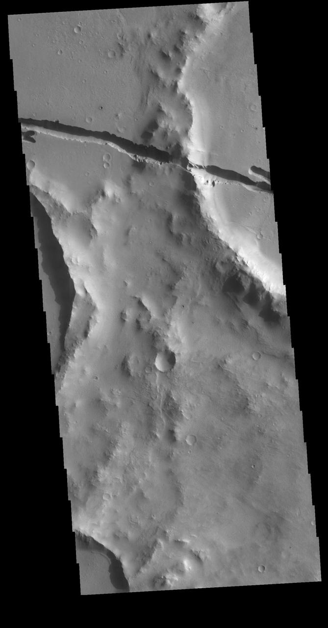 Today's VIS image shows a section of Cerberus Fossae. Located southeast of the Elysium Planitia volcanic complex, the linear graben near the top of the image was created by tectonic forces related to the volcanic activity. The graben are sources of both channels and significant volcanic flows. As seen in this image, the graben cuts across features such as hills, indicating the relative youth of the tectonic activity. Graben form where extensional tectonic forces allows blocks of material to subside between paired faults. Orbit Number: 79944 Latitude: 9.53204 Longitude: 158.706 Instrument: VIS Captured: 2019-12-22 21:50 https://photojournal.jpl.nasa.gov/catalog/PIA23743