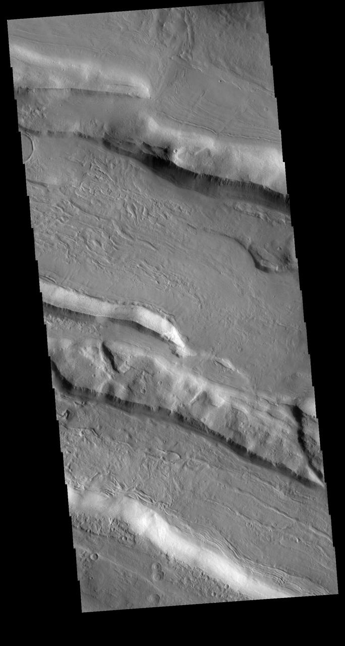 This VIS shows part of Acheron Fossae. Acheron Fossae is the highly fractured, faulted and deformed terrain located 1,050 kilometers (650 miles) north of the large shield volcano Olympus Mons. Lava flows from Olympus Mons at the base of Acheron Fossae show that the fossae predate the flows. The scarps visible in this image are approximately one kilometer (3,300 feet) high.  Orbit Number: 79929 Latitude: 37.9951 Longitude: 227.289 Instrument: VIS Captured: 2019-12-21 16:21  https://photojournal.jpl.nasa.gov/catalog/PIA23747