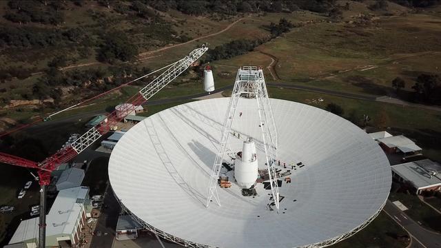 In a delicate operation, a 400-ton crane lifts the new X-band cone into the 70-meter (230-foot) Deep Space Network's Deep Space Station 43 (DSS-43) dish in Canberra, Australia. The new cone houses upgraded receiver and transmitter equipment for the 48-year-old antenna. One of several antennas located at the Canberra site, DSS-43 is the largest and responsible for transmitting commands to NASA's Voyager spacecraft. Since early March 2020, DSS43 has been offline for upgrades, which are expected to continue until January 2021.  https://photojournal.jpl.nasa.gov/catalog/PIA23796