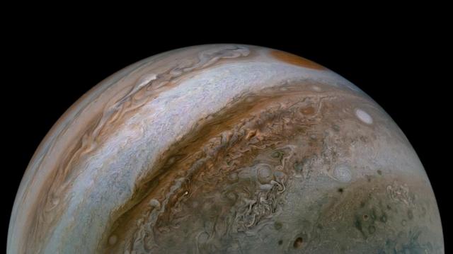This view of Jupiter's turbulent atmosphere from NASA's Juno spacecraft includes several of the planet's southern jet streams. Using data from Juno's instruments, scientists discovered that Jupiter's powerful atmospheric jet streams extend far deeper than previously imagined. Evidence from Juno shows the jet streams and belts penetrate about 1,800 miles (3,000 kilometers) down into the planet.  The storm known as the Great Red Spot is also visible on the horizon, nearly rotated out of view as Juno sped away from Jupiter at about 30 miles per second (48 kilometers per second), which is more than 100,000 mph (160,900 kilometers per hour).  Citizen scientist Tanya Oleksuik created this color-enhanced image using data from the JunoCam camera. The original image was taken on Dec. 30, 2020 as the Juno spacecraft performed its 31st close flyby of Jupiter. At the time, the spacecraft was about 31,000 miles (about 50,000 kilometers) from the planet's cloud tops, at a latitude of about 50 degrees South.  https://photojournal.jpl.nasa.gov/catalog/PIA23809