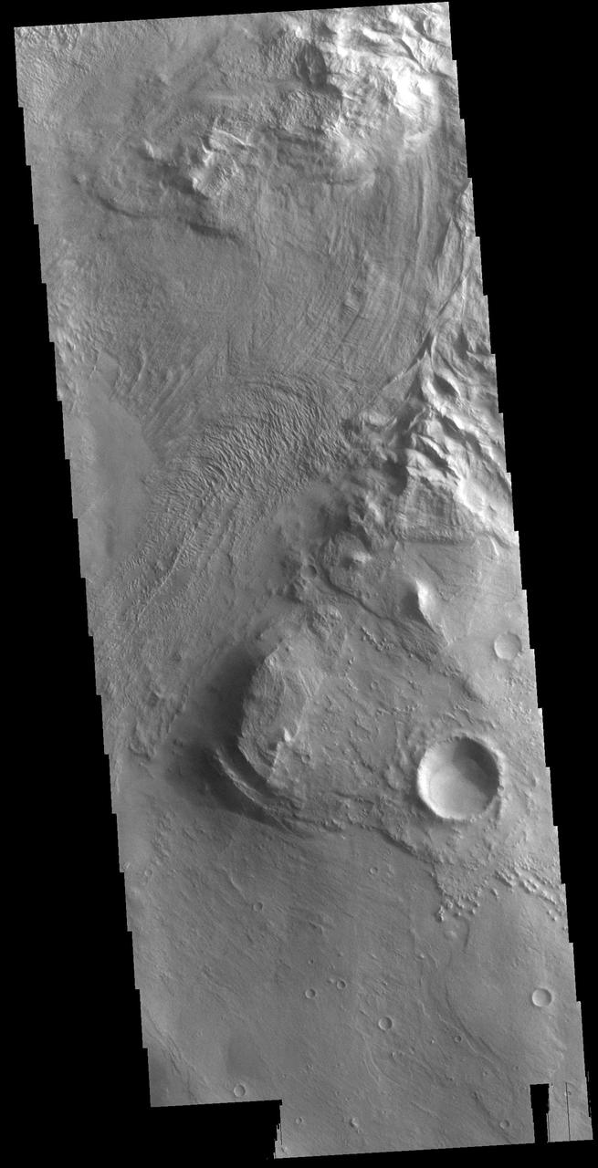 This VIS image is located in Melas Chasma. The linear and arcuate features at the top of the image are on the surface of a large landslide. This region of Melas Chasma is covered by several very large landslide deposits. Melas Chasma is part of the largest canyon system on Mars, Valles Marineris. At only 563 km long (349 miles) Melas is not the longest canyon, but it is the widest. Located in the center of Valles Marineris, it has depths up to 9,000 meters (30,000 feet) from the surrounding plains. In addition to landslide deposits, there are layered materials and sand dunes. There is evidence of both water and wind action as modes of formation for many of the interior deposits.  Orbit Number: 80264 Latitude: -11.2236 Longitude: 289.776 Instrument: VIS Captured: 2020-01-18 06:05  https://photojournal.jpl.nasa.gov/catalog/PIA23817