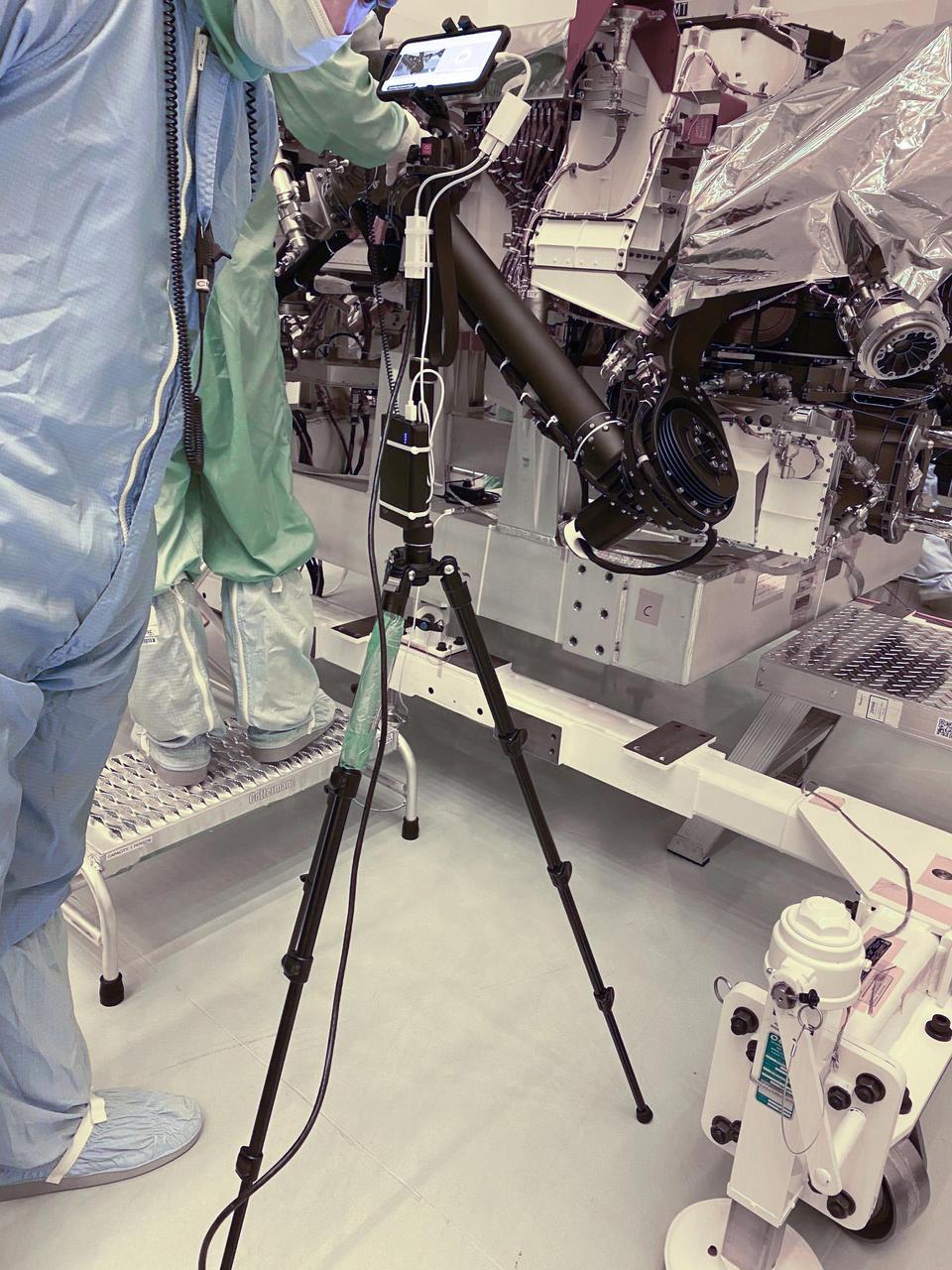 A technician points a smartphone camera at NASA's Perseverance rover during an inspection — called a "walkdown" — at Kennedy Space Center in Florida. The imagery from the phone was seen live by mission engineers watching from their home offices in Southern California. The image was taken on March 31, 2020.  https://photojournal.jpl.nasa.gov/catalog/PIA23825