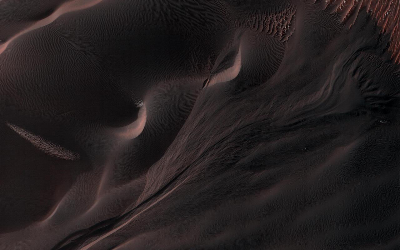 Gullies in the sand dunes of Matara Crater are very active. One large gully in particular has had major changes in every Martian winter since HiRISE began monitoring, triggered by the seasonal dry ice frost that accumulates each year. This time there was an especially large change, depositing a huge mass of sand. The sand divided into many small toes near its end, or perhaps many individual flows descended near the same spot. Additionally, a long sinuous ridge of sand was deposited. This could be a "levee" that formed along one side of a flow, but there is not much sand past the end of the ridge, so it might also be the main body of a flow. How many changes can you see in the cutout? https://ppj2.jpl.nasa.gov/catalog/PIA23853