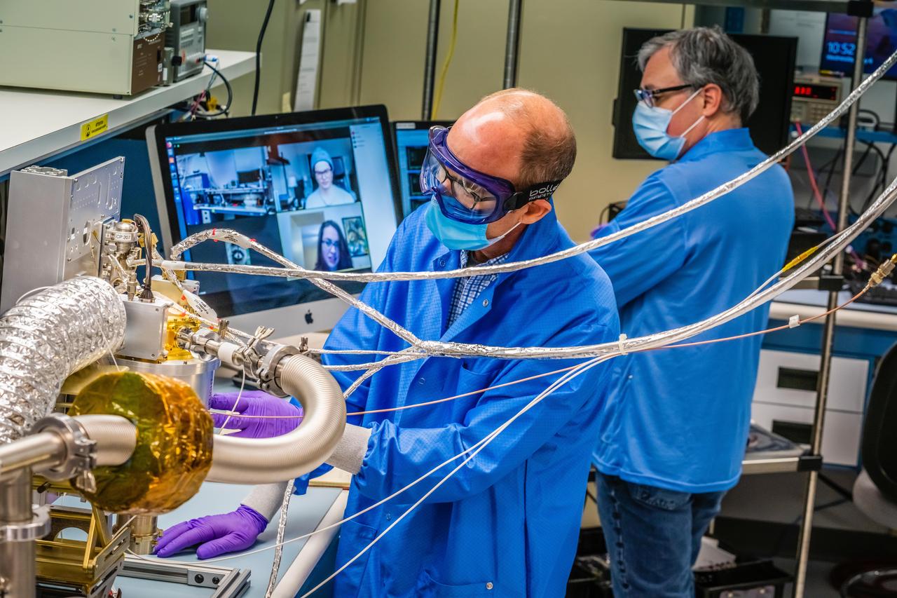 Engineers at the Johns Hopkins Applied Physics Laboratory (APL) in Laurel, Maryland, continue to make progress on Psyche's spectrometer while observing COVID-19 safety procedures. Engineers John Goldsten (left) and Sam Fix work on the Gamma Ray/Neutron Spectrometer (GRNS) instrument that will launch aboard the Psyche spacecraft in 2022 to detect, measure and map the asteroid Psyche's elemental composition. The instrument's team at APL moved the majority of its work to video conferencing, which has enabled the team to whittle operations down to requiring just one or two staff members on campus once or twice a week.  https://photojournal.jpl.nasa.gov/catalog/PIA23880