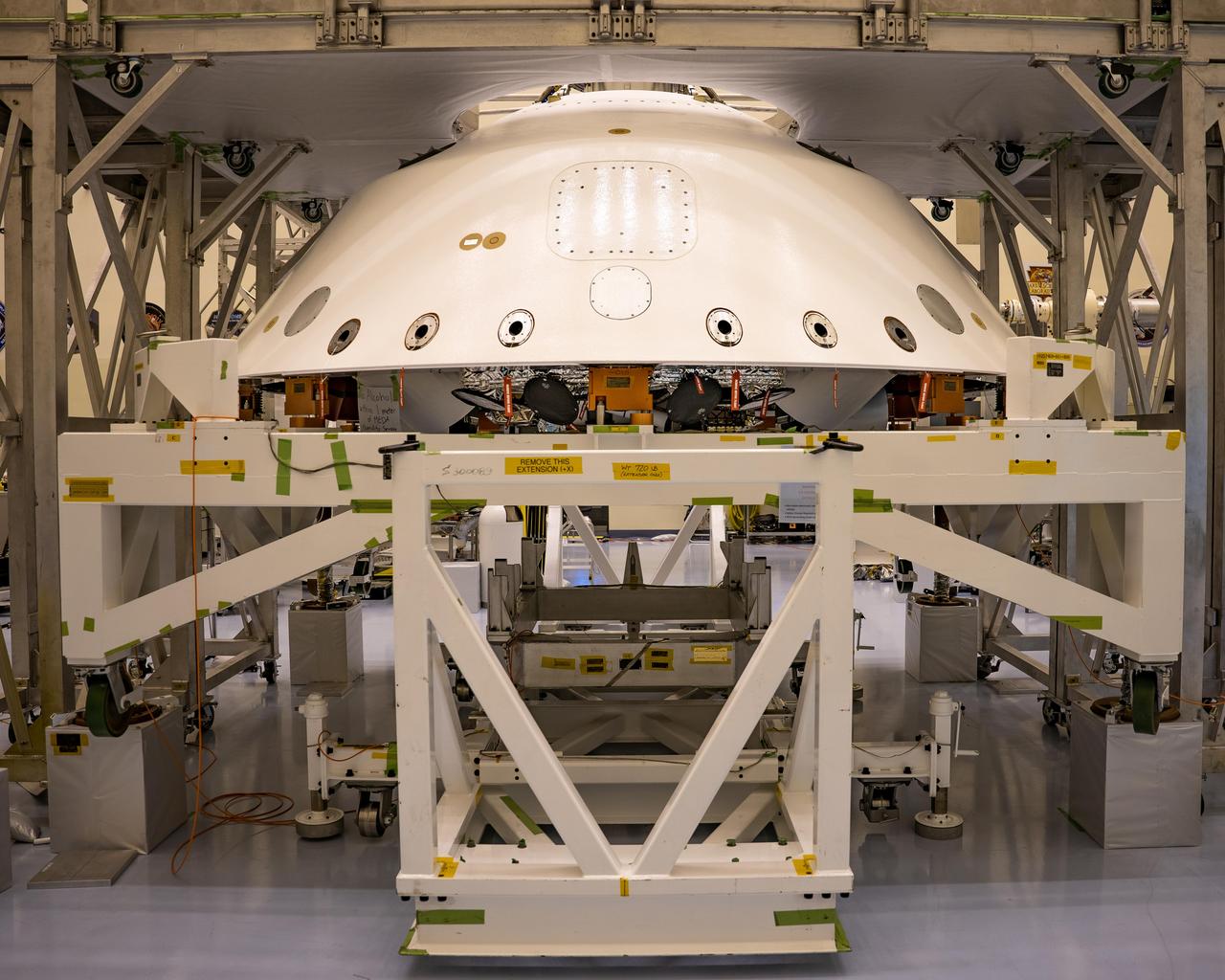 The cone-shaped back shell for NASA's Perseverance rover mission sits on a support structure in this April 29, 2020, image from Kennedy Space Center in Florida. Along with the heat shield, the back shell provides protection for the rover and descent stage during Martian atmospheric entry. Portions of the descent stage and rover, stacked one on top of the other, can be seen in the open area directly below the lower edge of back shell.  https://photojournal.jpl.nasa.gov/catalog/PIA23885