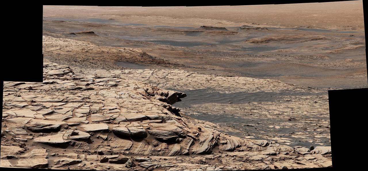 Stitched together from 28 images, this view from NASA's Curiosity Mars rover was captured on April 9, 2020, the 2,729th Martian day, or sol, of the mission after the rover ascended a steep slope, part of a geologic feature called "Greenheugh Pediment." In the foreground is the crusty sandstone cap that stretches the length of the pediment, forming an overhanging ledge in some parts. At center is the "clay-bearing unit," a region with a unique story to tell about the history of water on Mount Sharp, the 3-mile-tall (5-kilometer-tall) mountain Curiosity has been ascending since 2014. In the distance at the top of the image is the floor of Gale Crater, which is 96 miles (154 kilometers) wide.  https://photojournal.jpl.nasa.gov/catalog/PIA23974