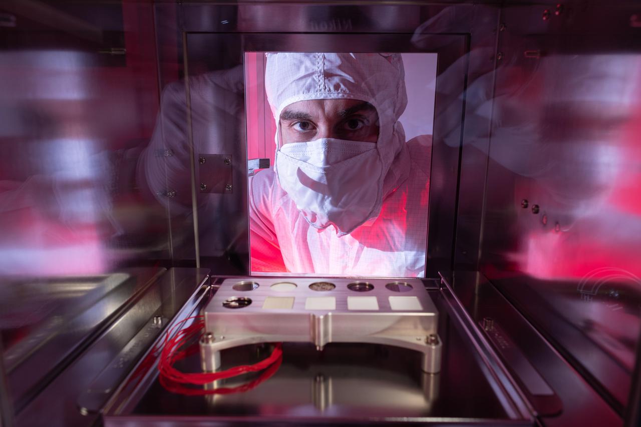 NASA scientist Trevor Graff peers at a calibration target, which will help fine-tune settings on the Scanning Habitable Environments with Raman & Luminescence for Organics and Chemicals (SHERLOC) instrument carried aboard NASA's Perseverance Mars rover. The calibration target is housed inside a special environmental chamber that was used to ship it from NASA's Johnson Space Center, Houston, to the agency's Jet Propulsion Laboratory in Southern California, where the target was added to the rover.  There are 10 kinds of materials on SHERLOC's calibration target, including a fragment of a Martian meteorite and five of the first spacesuit materials sent to Mars. They'll be observed to see how they hold up in the intense radiation on the Martian surface.  https://photojournal.jpl.nasa.gov/catalog/PIA23979