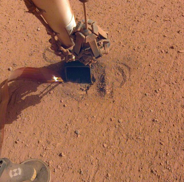 NASA's InSight lander retracted its robotic arm on Oct. 3, 2020, revealing the spot where the self-digging "mole" is attempting to burrow into the planet's surface. Attached to the mole is the copper-colored ribbon, which is laden with temperature sensors designed to measure the heat flow within Mars. In the months to come, the scoop seen on the end of the arm will be used to scrape and tamp down soil on top of the mole, in hopes of helping it dig. Movie available at https://photojournal.jpl.nasa.gov/catalog/PIA24098