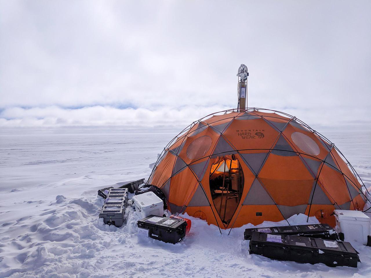 During 2019 field tests near Greenland's Summit Station, a high-elevation remote observing station, the WATSON (Wireline Analysis Tool for the Subsurface Observation of Northern ice sheets) instrument is put through its paces to seek out signs of life, or biosignatures, 360 feet (110 meters) down a borehole. In this photograph, the winch that holds the drill pokes out the top of the drill tent.      WATSON could one day be launched aboard a robotic mission to seek out biosignatures on the ocean moons of Enceladus, Europa, or even Titan. The WATSON team hopes to test the instrument in a variety of cold locations on Earth to see how the distribution and variety of biosignatures change depending on where they are. By testing WATSON in different Earth analogs — areas on Earth that can stand in for those on other worlds — scientists would be able to better understand the chemical fingerprints of any biosignatures detected on other worlds.  https://photojournal.jpl.nasa.gov/catalog/PIA24169