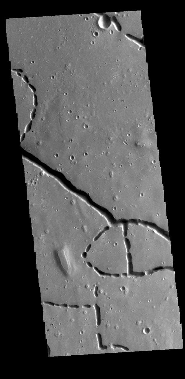 This VIS image is located in the northern portion of Hephaestus Fossae. Hephaestus Fossae is a complex channel system in Utopia Planitia near Elysium Mons. It has been proposed that the channels formed by the release of melted subsurface ice during the impact event that created a large crater southeast of this image. Additionally, the nearby Elysium volcanic center created subsurface heating that may have played a part in creating both Hephaestus Fossae and Hebrus Valles to the north. The right angle intersections indicate there is some tectonic activity in the region, and the circular depressions indicate surface collapse into subsurface voids. Hephaestus Fossae is a very complex set of features. Orbit Number: 85960 Latitude: 21.3916 Longitude: 122.454 Instrument: VIS Captured: 2021-05-01 06:13 https://photojournal.jpl.nasa.gov/catalog/PIA24212