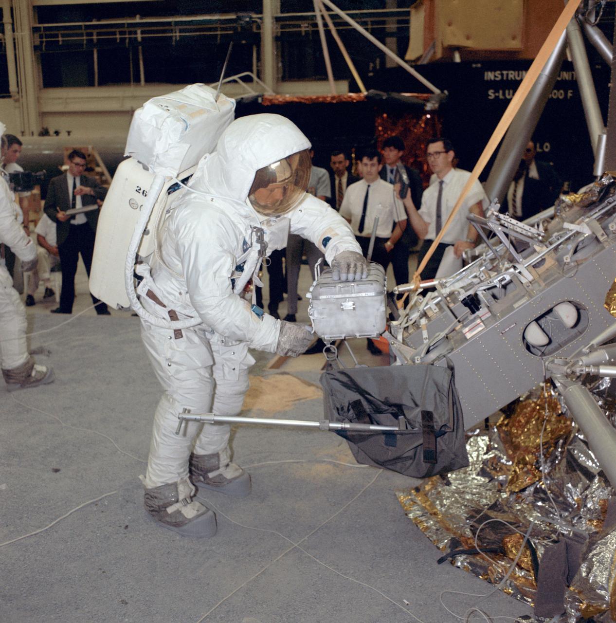 Apollo 11 commander Neil Armstrong works with an Apollo Lunar Sample Return Container during a two-and-a-half-hour lunar surface simulation training exercise. The image was taken on Apr. 18, 1969, in Building 9 at the Manned Spacecraft Center in Houston, Texas.  The sample tubes carried by NASA's Mars 2020 Perseverance rover are destined to carry the first samples in history from another planet back to Earth. Future scientists will use these carefully selected representatives of Martian rock and regolith (broken rock and dust), to look for evidence of potential microbial life present in Mars' ancient past and to answer other key questions about Mars and its history. Perseverance will land at Mars' Jezero Crater on Feb. 18, 2021.  https://photojournal.jpl.nasa.gov/catalog/PIA24297