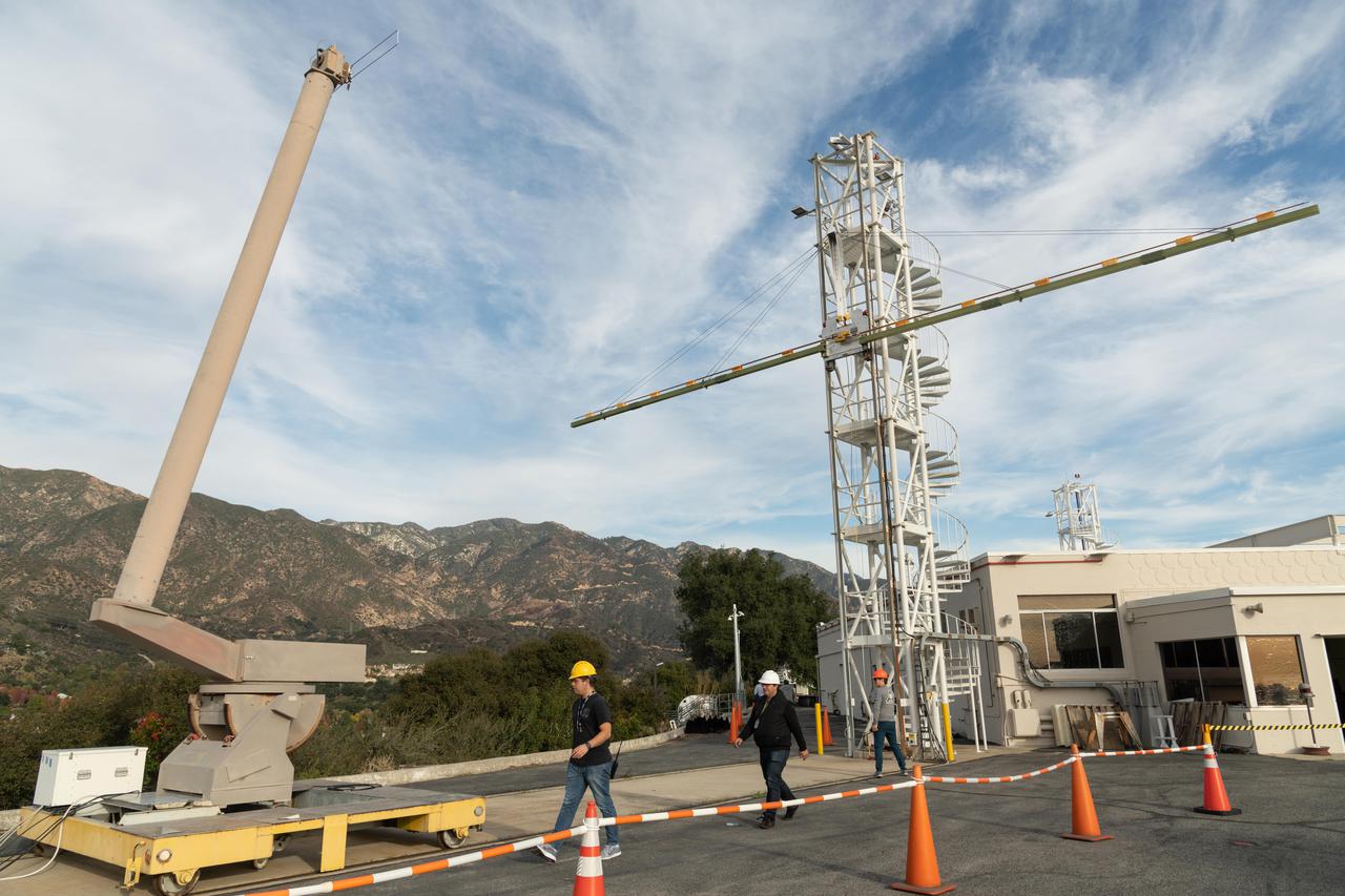 Engineers at NASA's Jet Propulsion Laboratory in Southern California test an engineering model of a high-frequency (HF) radar antenna that makes up part of NASA's Europa Clipper radar instrument on Dec. 17, 2019. The antenna is a 59-foot-long (18-meter-long) narrow copper tube held straight by several cables and a cross bar on the tower at right. In space, the copper tube will stick out straight on its own, but in Earth's gravity, the antenna requires supports to keep it straight for testing. The mobile tower at left holds a model of the VHF (very high-frequency) antenna so that engineers could measure the amount of energy coupled from one antenna to the other.  Europa Clipper's radar instrument is called Radar for Europa Assessment and Sounding: Ocean to Near-surface, or REASON. As the spacecraft orbits Jupiter and surveys its icy moon Europa, REASON will use HF and VHF radio signals to penetrate up to 18 miles (30 kilometers) into the icy shell that covers Europa. The radio waves will bounce off subsurface features and return to the spacecraft to create images of the ice layers' internal structure. REASON will help scientists look for the moon's suspected ocean, measure ice thickness, and better understand the icy shell's interior. The instrument will also study the elevation, properties, and roughness of Europa's surface, and will prowl Europa's upper atmosphere for signs of plume activity.  The antennae were built for NASA by Heliospace Corporation in Berkeley, California, and the University of Texas at Austin is the lead institution for REASON. The testing was conducted at JPL's Mesa Antenna Measurement Facility, which sits on a high plateau.  With an internal global ocean twice the size of Earth's oceans combined, Europa may have the potential to harbor life. The Europa Clipper orbiter will swoop around Jupiter on an elliptical path, dipping close to the moon on each flyby to collect data. Understanding Europa's habitability will help scientists better understand how life developed on Earth and the potential for finding life beyond our planet. Europa Clipper is aiming for a launch readiness date of 2024.  https://photojournal.jpl.nasa.gov/catalog/PIA24323
