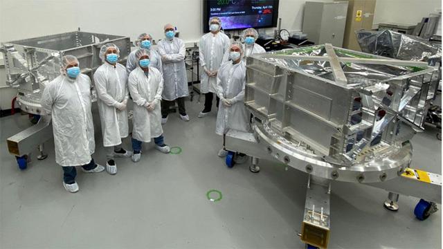 Engineers and technicians in a clean room at NASA's Jet Propulsion Laboratory in Southern California stand between the thick-walled aluminum vault and its duplicate (at rear) that they helped build for the agency's Europa Clipper spacecraft. As Europa Clipper orbits Jupiter, conducting flybys of its moon Europa to gather science data, the vault will protect the spacecraft's electronics from Jupiter's intense radiation.  In 2022, the vault will be bolted to the top of Europa Clipper's propulsion module and affixed with cabling, to provide communications and control across the entire spacecraft. The duplicate test model of the vault gives engineers a way to test procedures before assembly of flight hardware. The test model also will be subjected to stress testing to confirm that the design will work when Europa Clipper operates in deep space.  With an internal global ocean under a thick layer of ice, Europa may have the potential to harbor existing life. Europa Clipper will swoop around Jupiter on an elliptical path, dipping close to the moon on each flyby. Understanding Europa's habitability will help scientists better understand how life developed on Earth and the potential for finding life beyond our planet. Europa Clipper is set to launch in 2024.  https://photojournal.jpl.nasa.gov/catalog/PIA24479